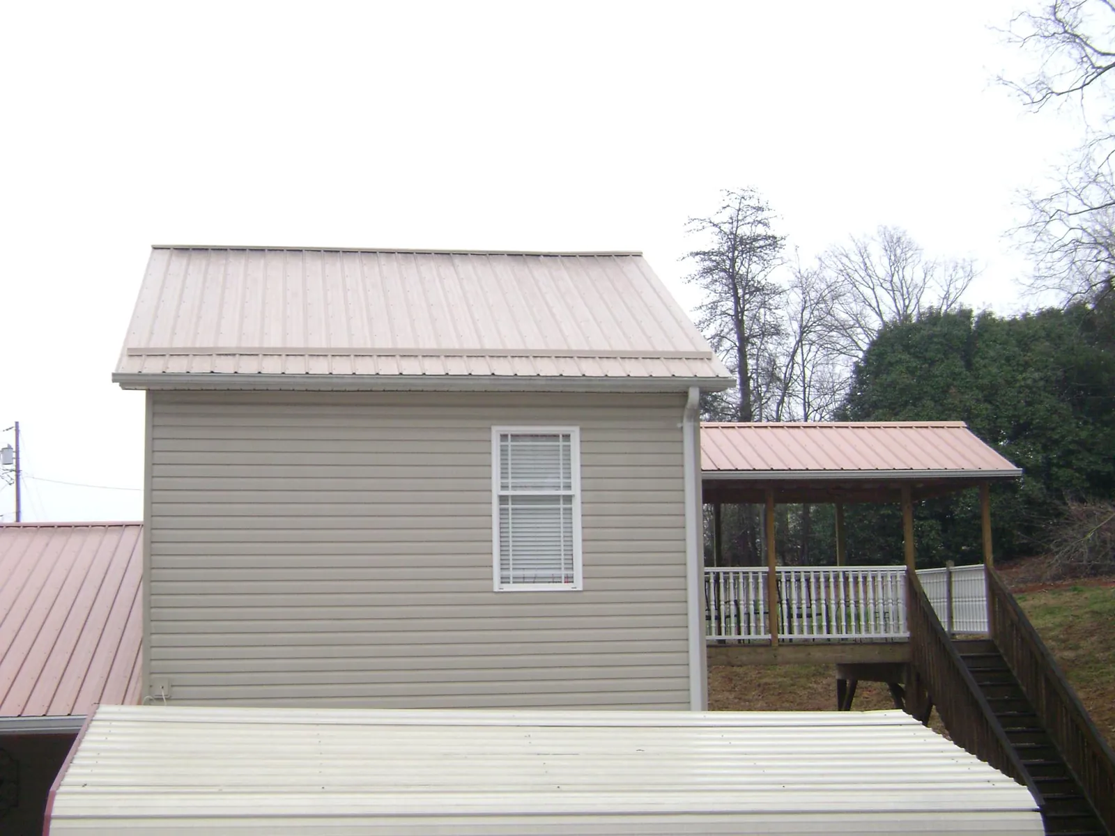 Tan metal roofs on a two story addition and attached porch, from a Roof Replacement job in Kimberly